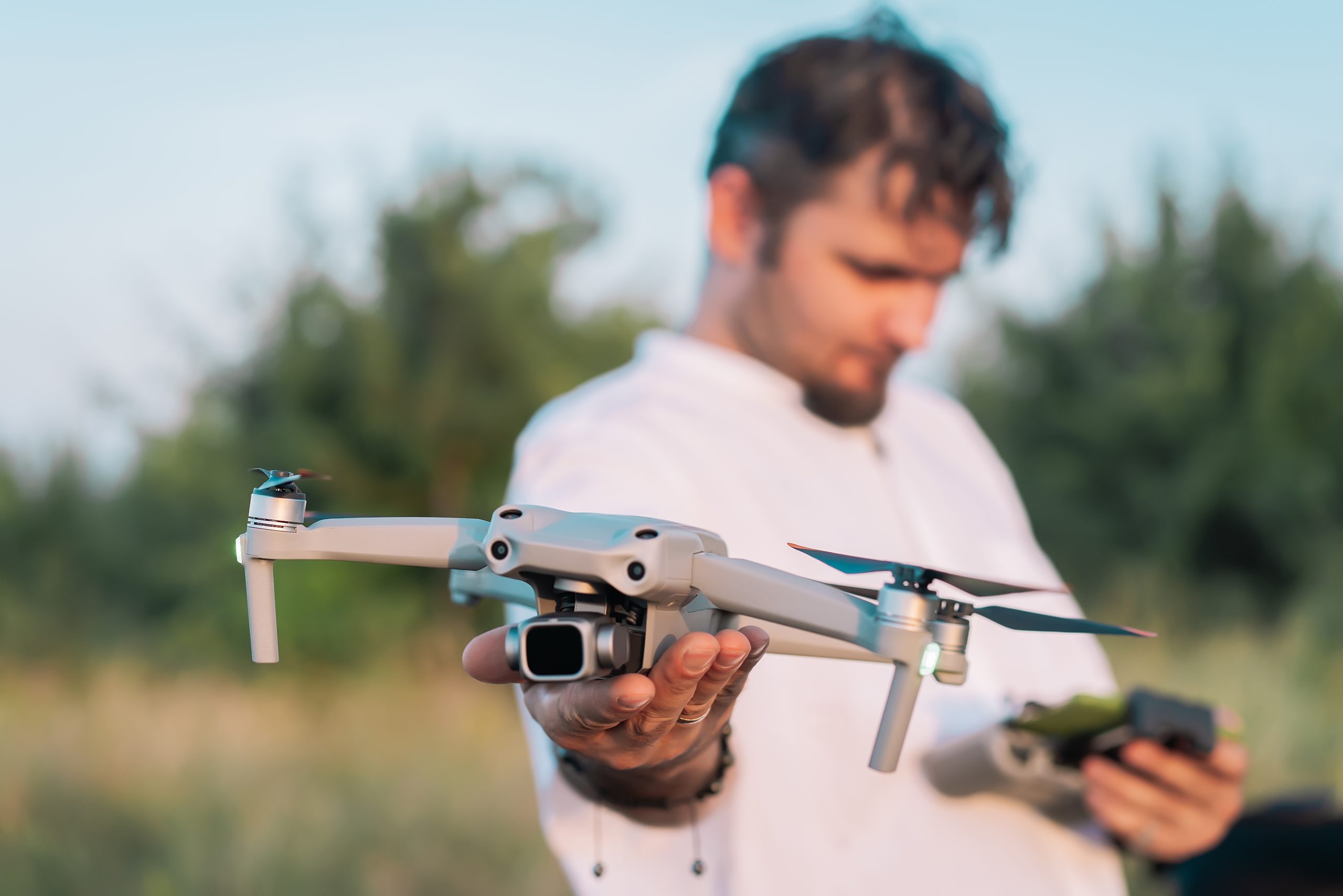 Man holding compact amateur drone before flight. Piloting quadcopter outdoors. Aerial shooting. Filming nature from high