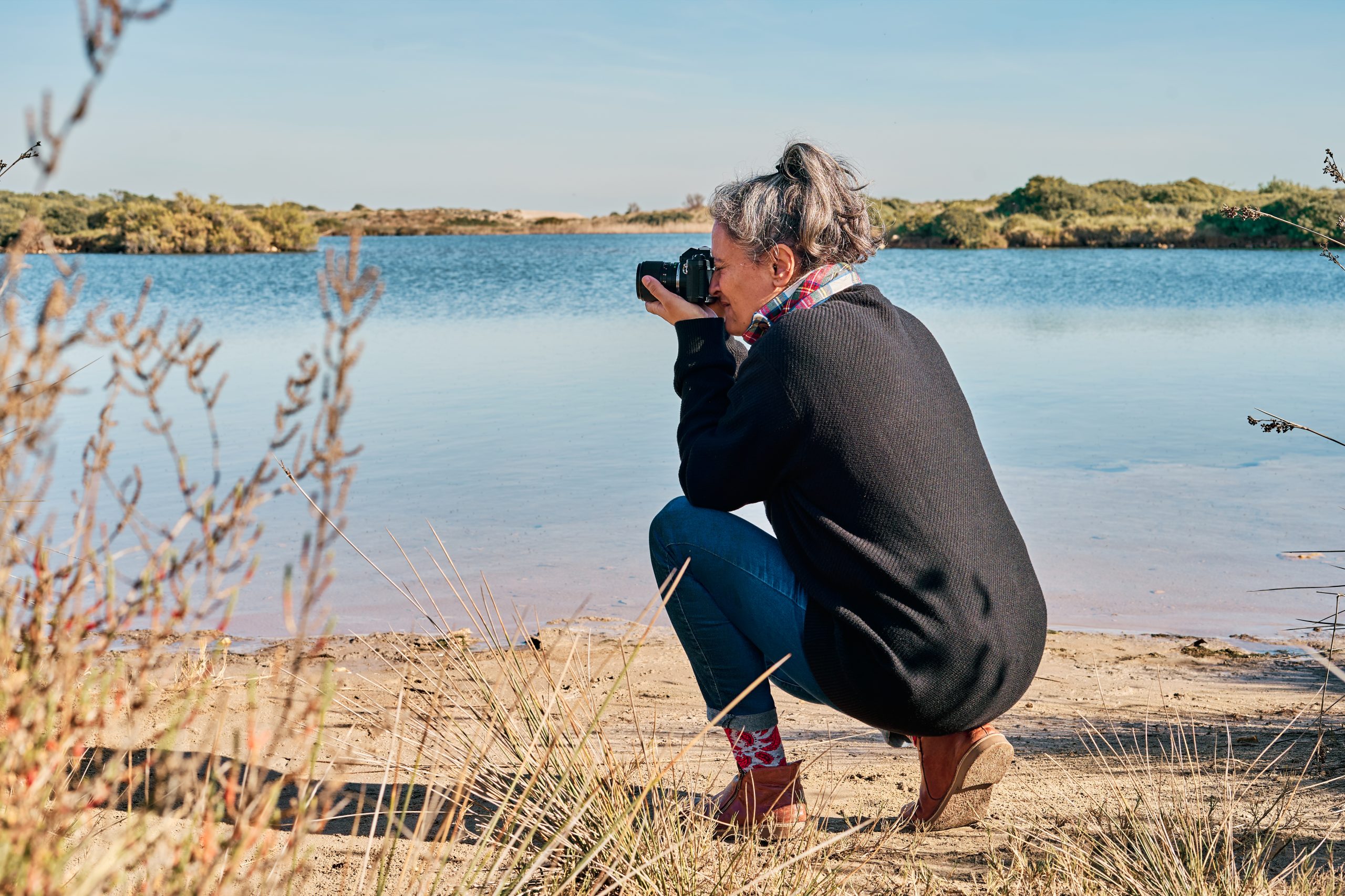 Woman crouching doing landscape photography at lake